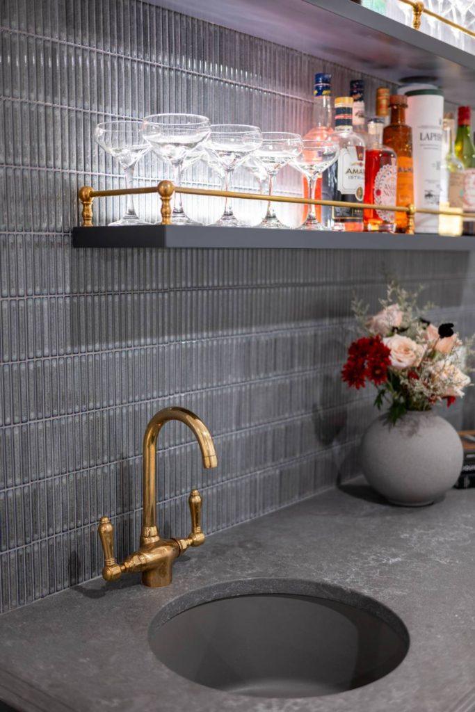 a sink with a gold faucet and a vase of flowers