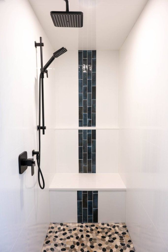 a bathroom with a tiled shower and black and white tile